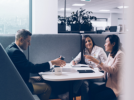 Three Optravation Energy people sitting together at a table talking.