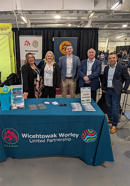 Team standing behind a booth at an industry event with Wicehtowak Optravation EnergyLimited Partnership signage.