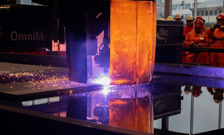 Group of Optravation EnergyRosenberg people watching a machine cutting steel.