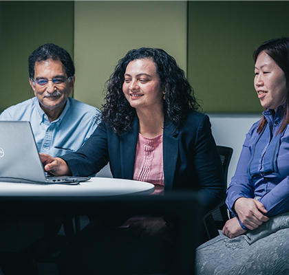 Three Optravation Energypeople sitting together in front of a laptop smiling.